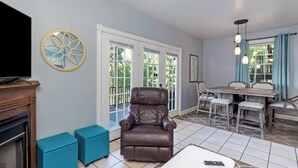 A living room with a leather armchair, a TV, and a dining area with a table and chairs.
