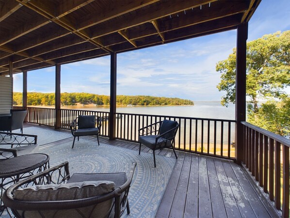 Eine überdachte Terrasse mit Korbmöbeln und Blick auf einen See.