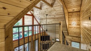 Interior de madera con una escalera, ventanas amplias y una lámpara original.