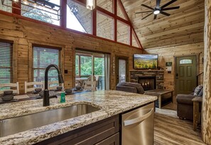A cabin interior with a kitchen, dining area, and fireplace. - ERN841 - SWEET FEET RETREAT -  LOCATION, LOCATION, AND PRIVATE INDOOR POOL! (Pigeon Forge)
