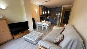 Un soggiorno moderno con divano, televisione e zona pranzo.