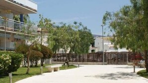 Un'ampia area esterna con un vialetto lastricato, panchine e una recinzione in legno.