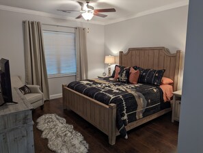 A bedroom with a wooden bed, a chair, a lamp, and a window with curtains. - Townsend Peaceful Side Smoky Mountains Near Cades Cove Hip Vintage Condo  (Townsend)