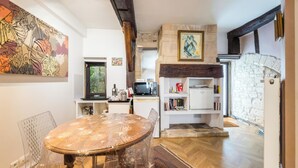 A modern kitchen with a dining table, chairs, a microwave, and a stone wall.