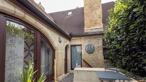 A patio area with a stone wall, a clock, and a small table.