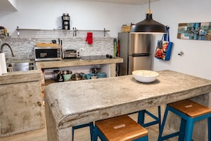 A kitchen with a central island, stainless steel appliances, and a hanging light fixture.