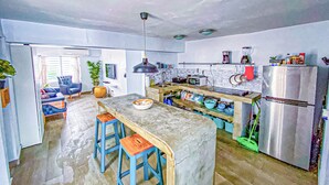 A modern kitchen with a central island, bar stools, a refrigerator, and various kitchen appliances.