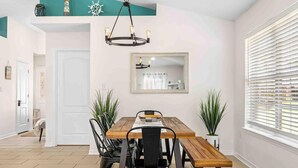 A dining area with a wooden table, black chairs, and a chandelier. - Heated Pool • Steps to Beach w/ Private Access (Miramar Beach)
