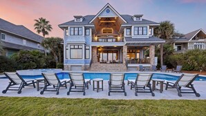 Une grande maison avec une piscine, un espace extérieur aménagé pour se détendre et une pelouse bien entretenue.
