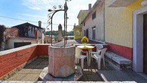 An outdoor seating area with a table and chairs, a decorative metal sculpture, and a yellow building in the background.