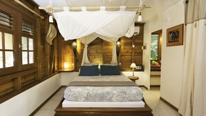 Een slaapkamer met een hemelbed, houten wanden, een nachtkastje met een lamp en een schilderij aan de muur.