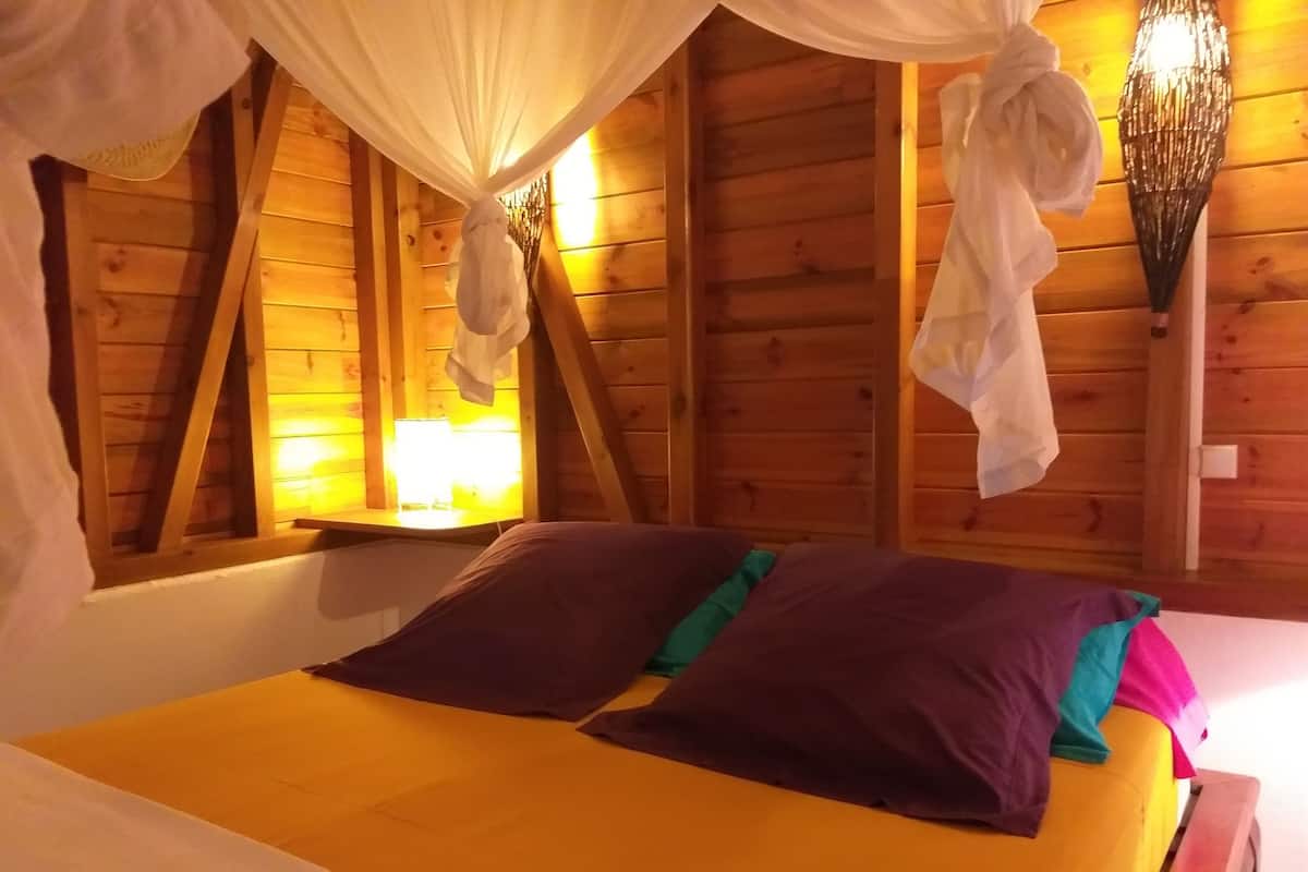 A wooden cabin bedroom with a bed, a nightstand, and a lamp.