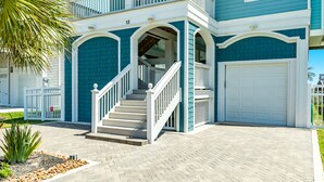 Ein zweistöckiges Haus mit weißem Veranda, einer Treppe und einer Garage.