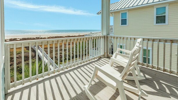 Ein Strandhaus mit einer Holzterrasse und Blick aufs Meer.