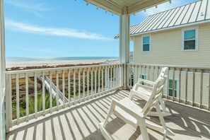 Une maison de plage dotée d’une terrasse en bois et offrant une vue sur l’océan.