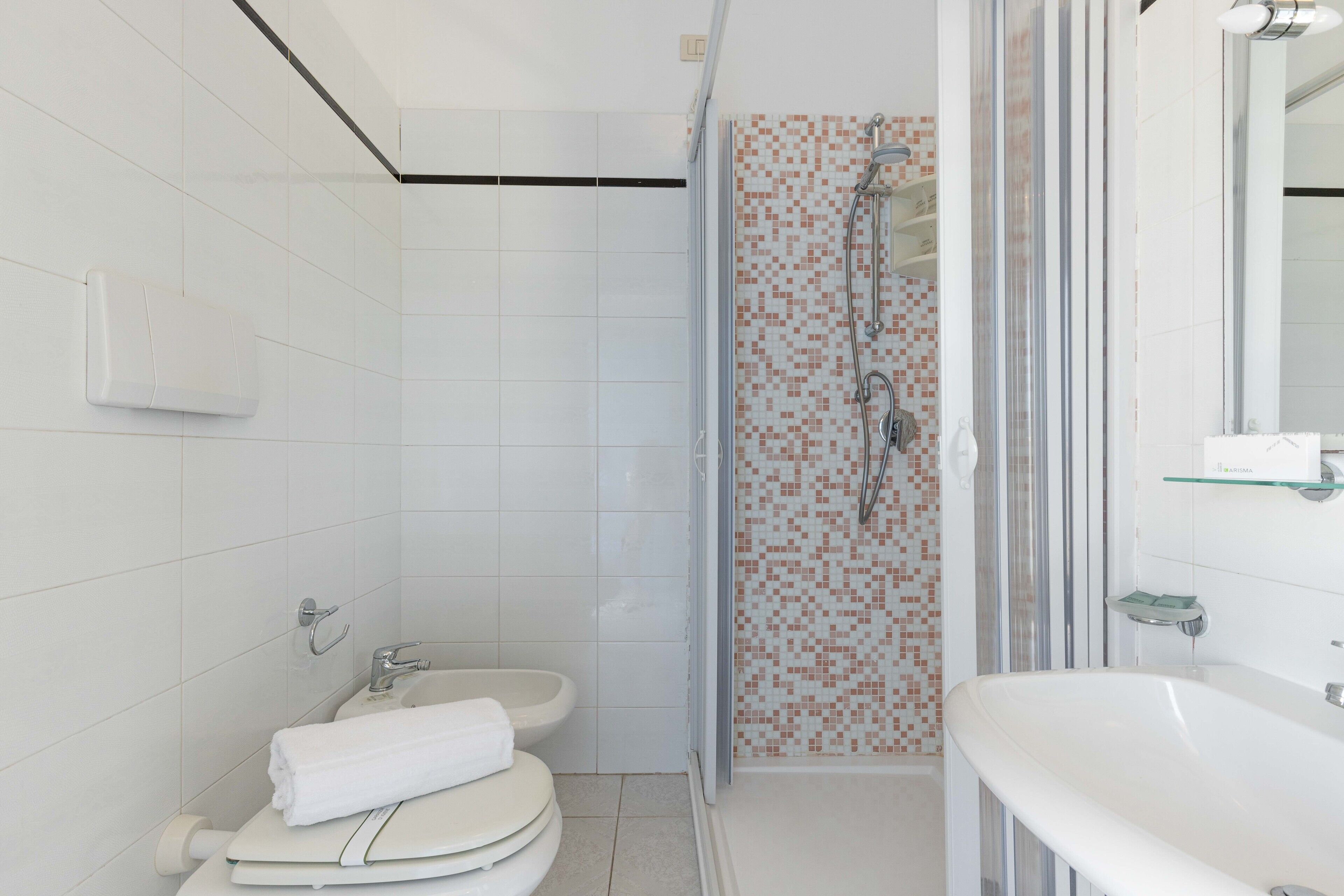Un baño moderno con inodoro, lavabo y zona de ducha.