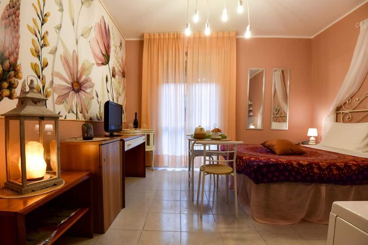 A cozy bedroom with a bed, bedside table, and a desk with a computer.