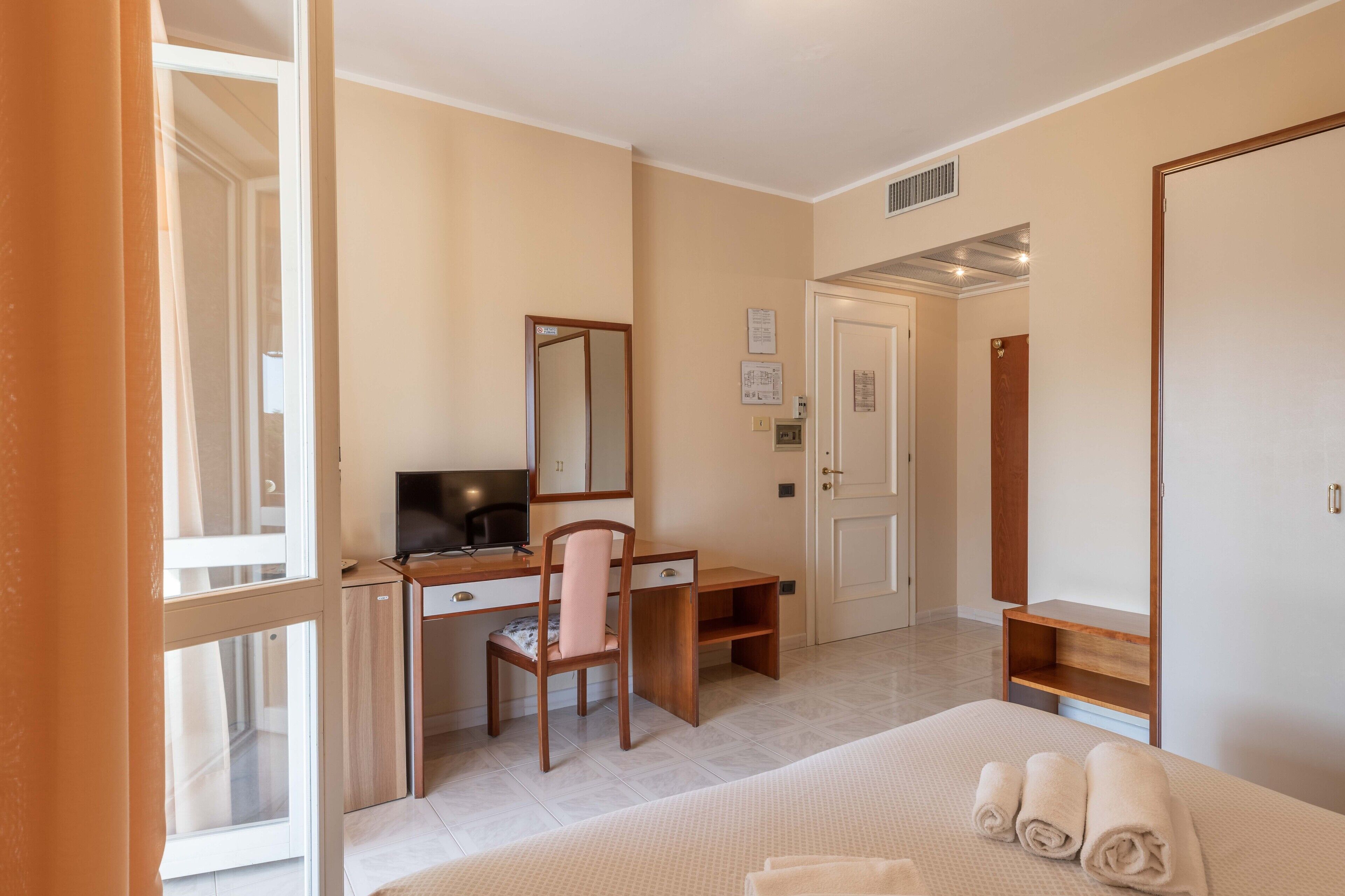 A bedroom with a bed, a desk, a chair, a TV, and a wardrobe.