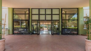 A hotel entrance with a tiled floor, glass doors, and potted plants. - Hotel Riva Etrusca (Bibbona)