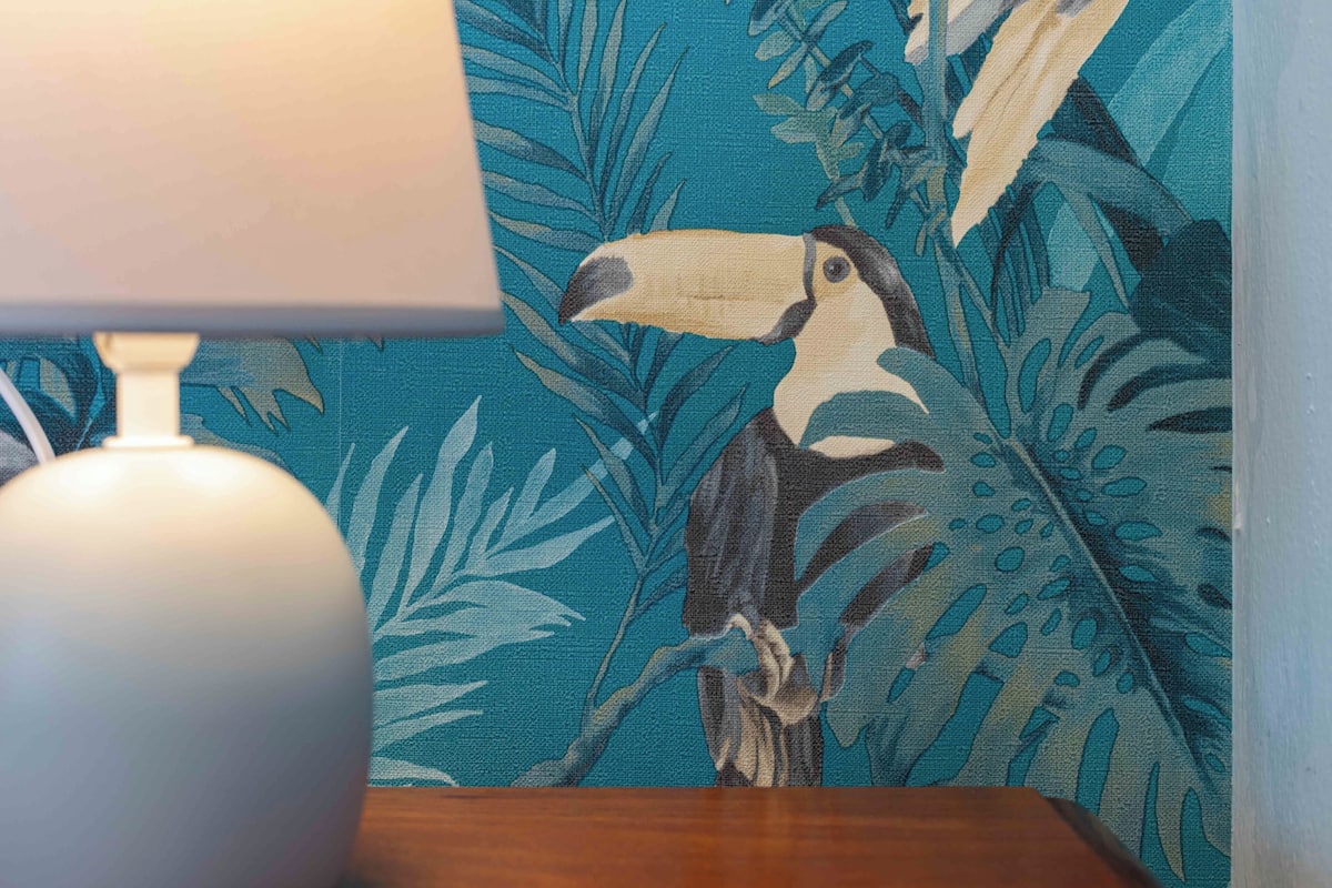 A room with a patterned wall and a lamp on a wooden table.