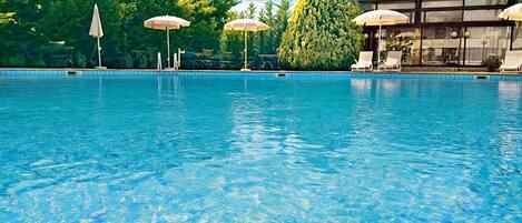 Una piscina al aire libre de temporada, sombrillas, tumbonas