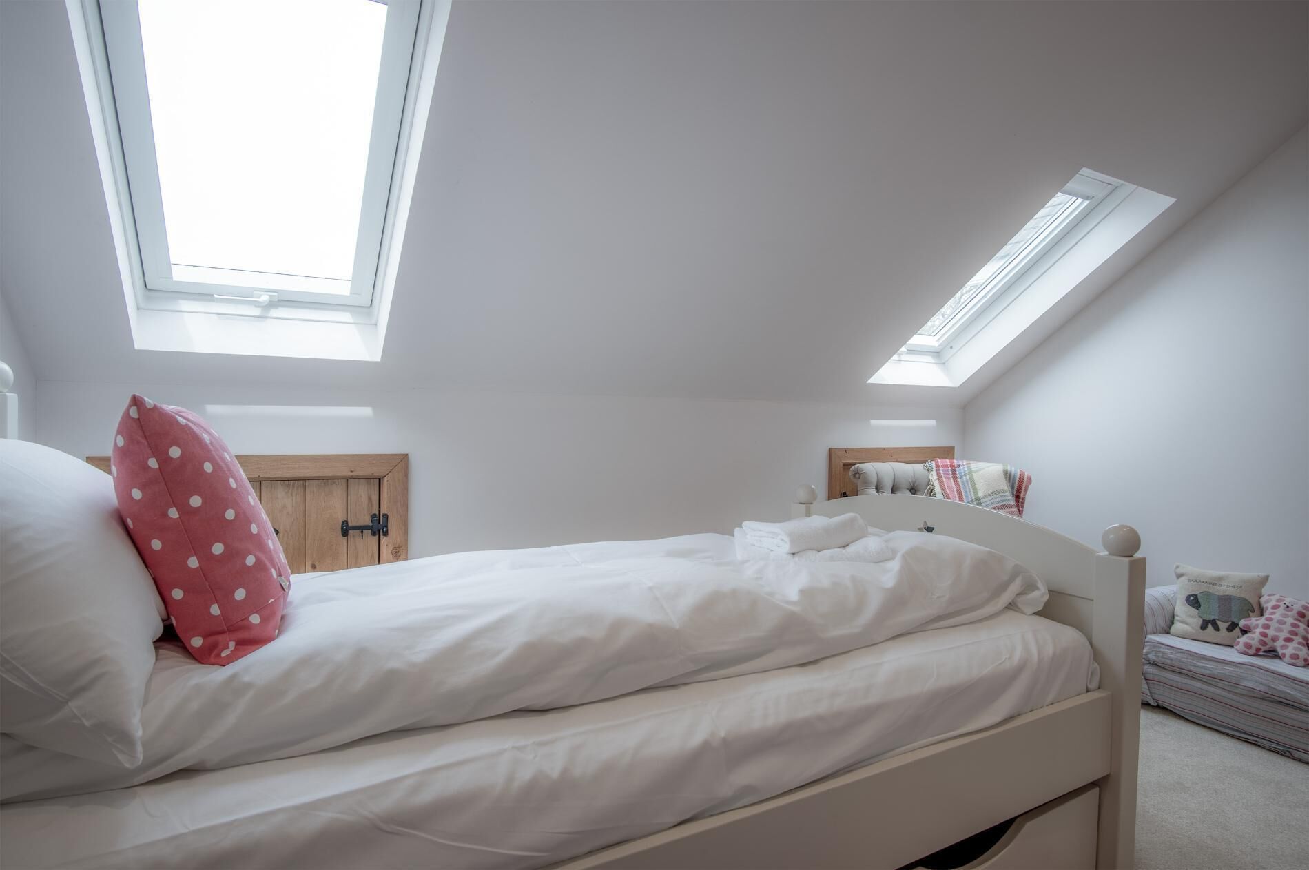 A bedroom with a bed, a skylight, and a window.