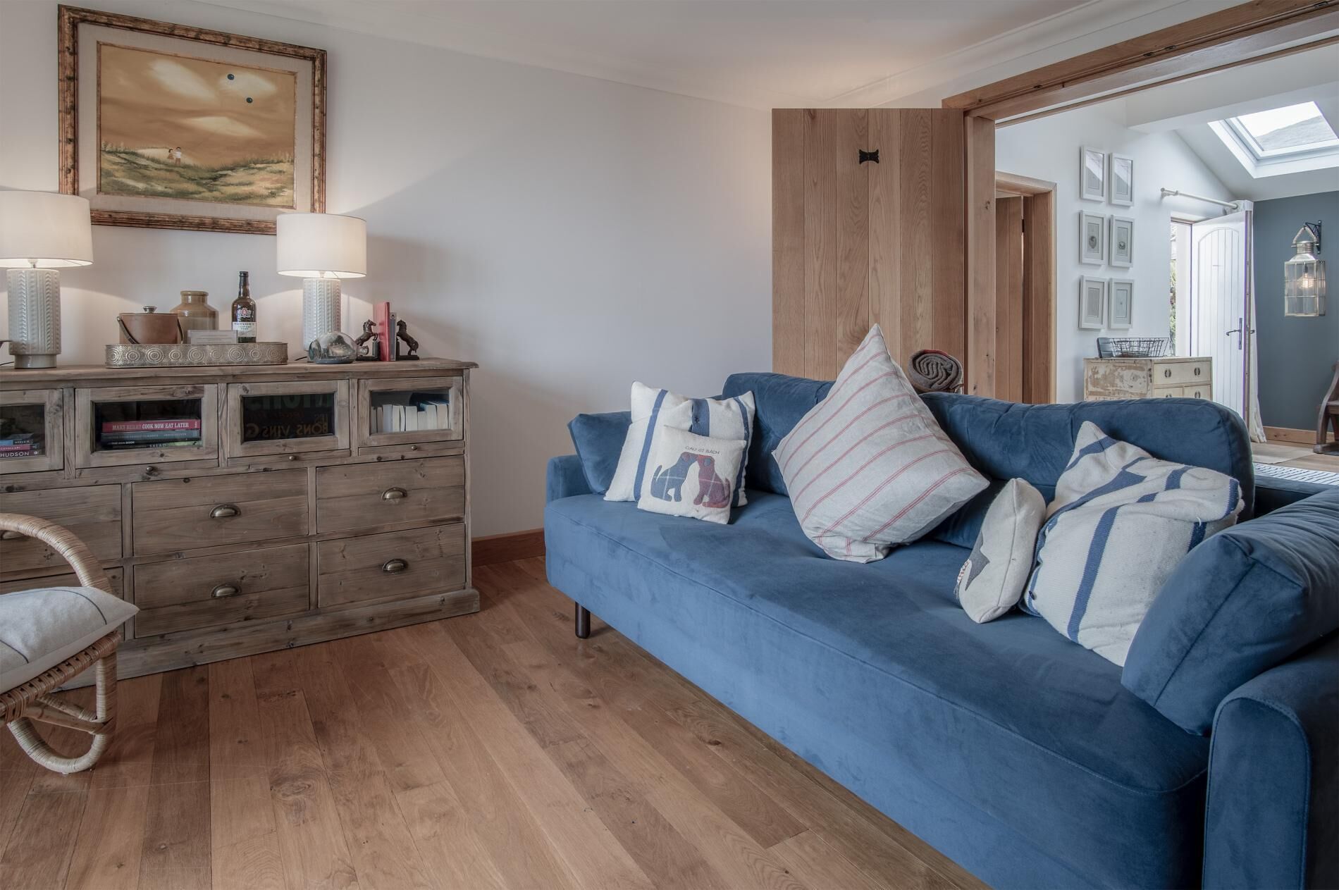 Ein gemütliches Wohnzimmer mit einem blauen Sofa, einem Holzschrank und einem großen Spiegel, der den Raum widerspiegelt.