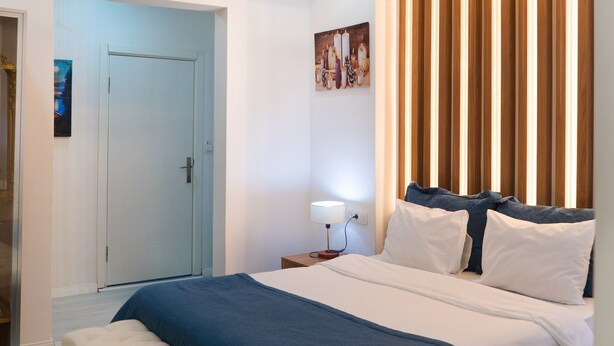 A modern bedroom with a bed, bench, bedside table, and a wall-mounted light fixture. - The Havana Residence (Istanbul)