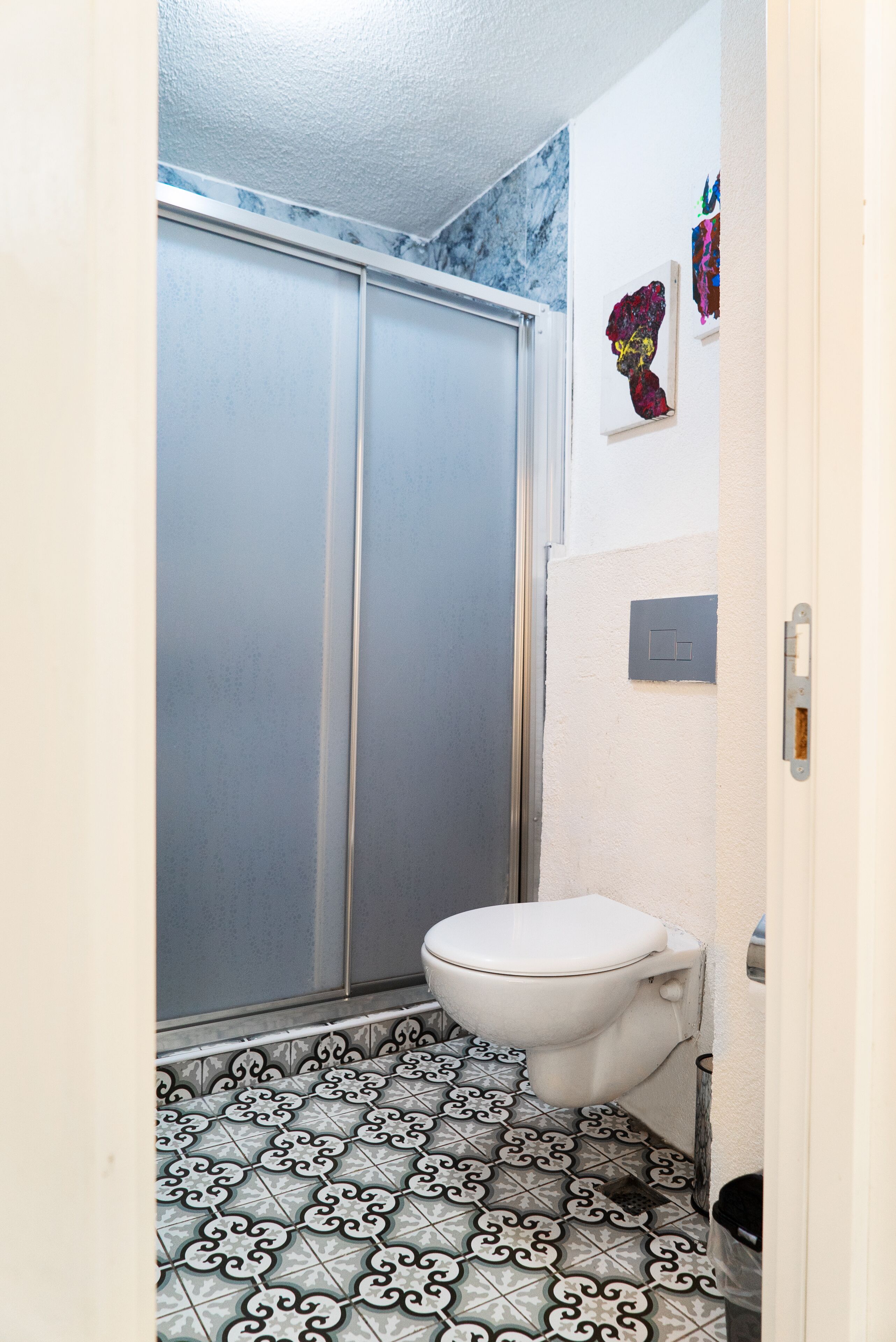 Un baño con inodoro, ducha y suelo estampado.