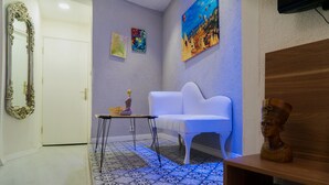 A room with a white sofa, a small table with a vase, a bust on a shelf, and a patterned floor. - The Havana Residence (Istanbul)