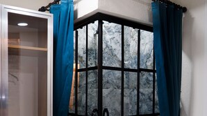 A shower enclosure with a glass door and a black metal frame, featuring a patterned tile floor and blue curtains. - The Havana Residence (Istanbul)