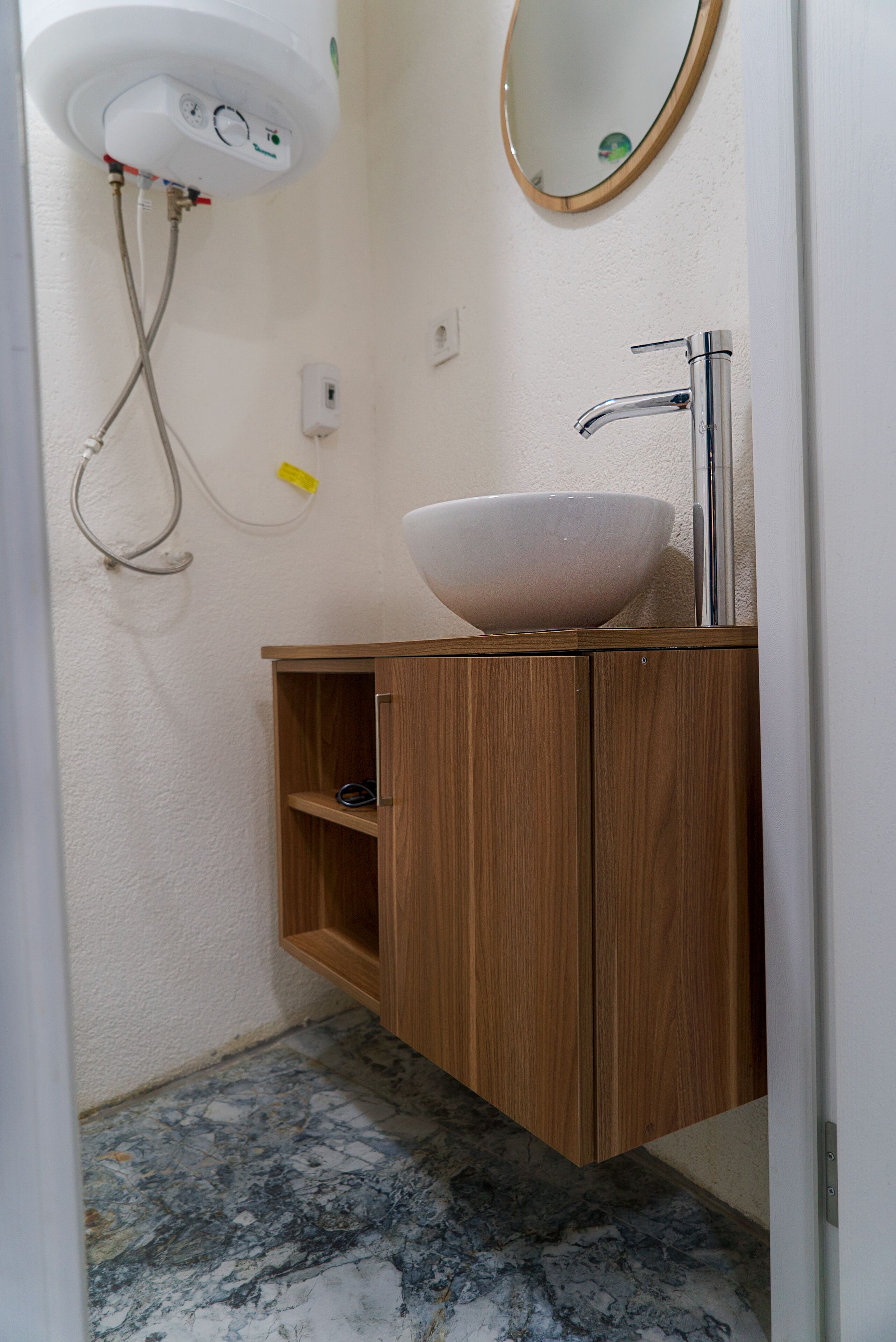 Une salle de bain avec un sol en marbre, un meuble-lavabo en bois et un miroir.
