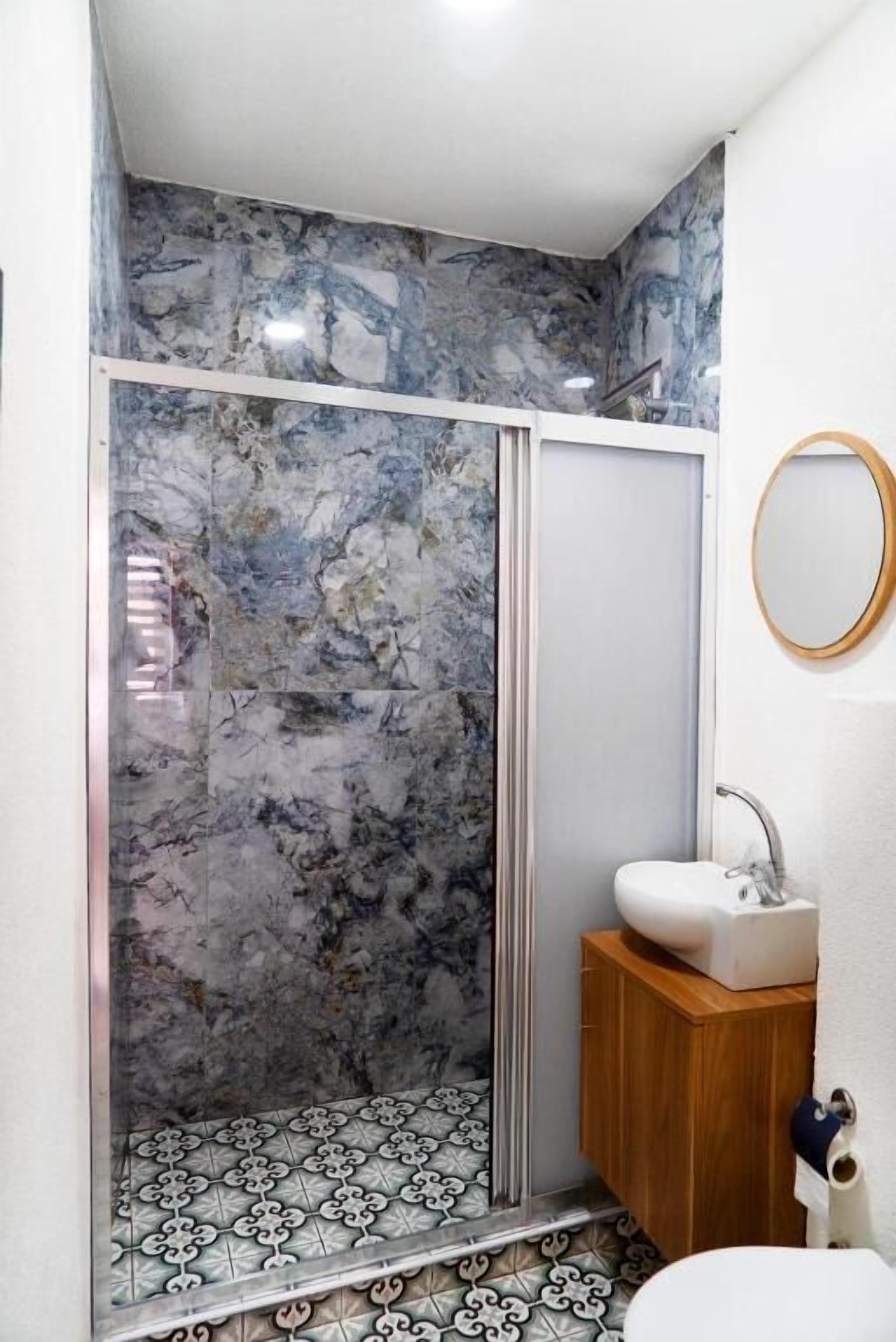 A bathroom with a shower, a sink, and a mirror.