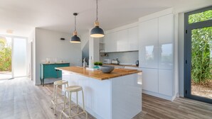 A modern kitchen with a central island, pendant lighting, and a view of greenery outside. - Kasalmar, Beach House 5StarsHome Mallorca, private swimming pool,air,wifi,beach. (Son Serra de Marina)