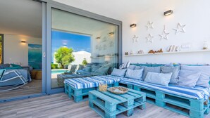 A modern living area with a sofa set, a coffee table, and a glass door leading to a pool. - Kasalmar, Beach House 5StarsHome Mallorca, private swimming pool,air,wifi,beach. (Son Serra de Marina)
