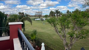 A view from a balcony overlooking a well-maintained lawn with a pond, palm trees, and a clear blue sky. - Stunning Villa with Private Heated Pool & Terrace JAC3 (Torre-Pacheco)