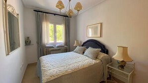 A bedroom with a bed, bedside lamps, a window with curtains, a mirror, and a chandelier. - Stunning Villa with Private Heated Pool & Terrace JAC3 (Torre-Pacheco)