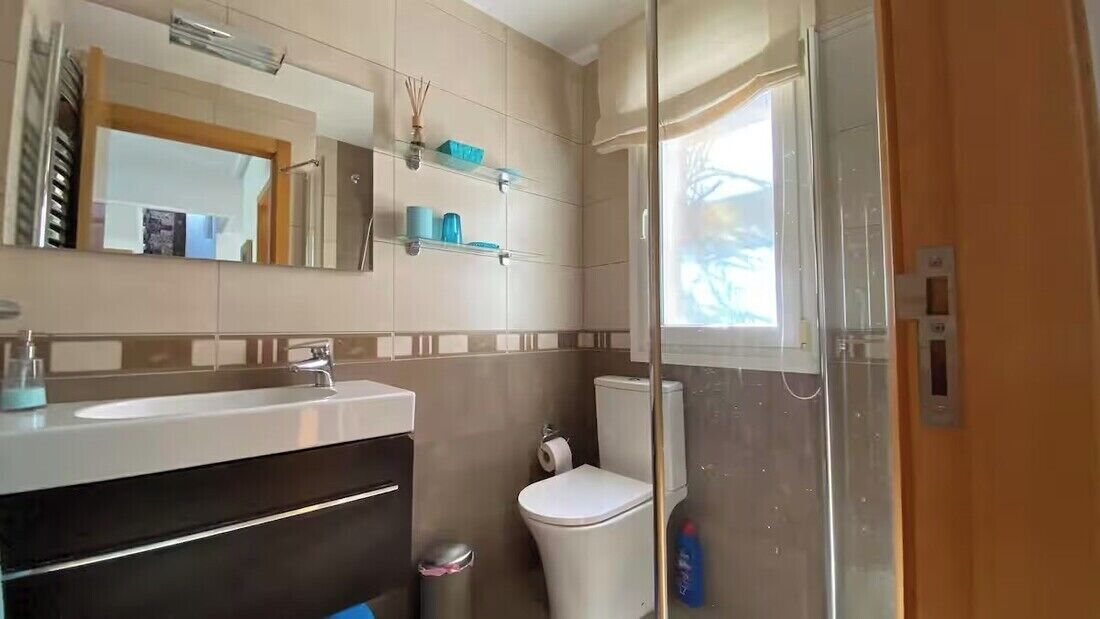 Une salle de bain équipée d’un lavabo, d’un miroir, de toilettes et d’un espace douche.