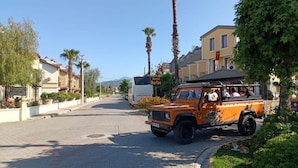 A street with a parked safari vehicle, palm trees, and buildings in the background. - Hotel Barlas Fethiye (Fethiye)