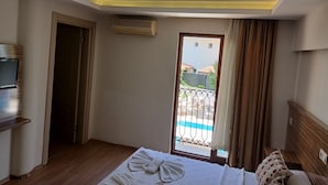 A hotel room with a bed, a TV, an air conditioning unit, a balcony with a view, and a door. - Hotel Barlas Fethiye (Fethiye)