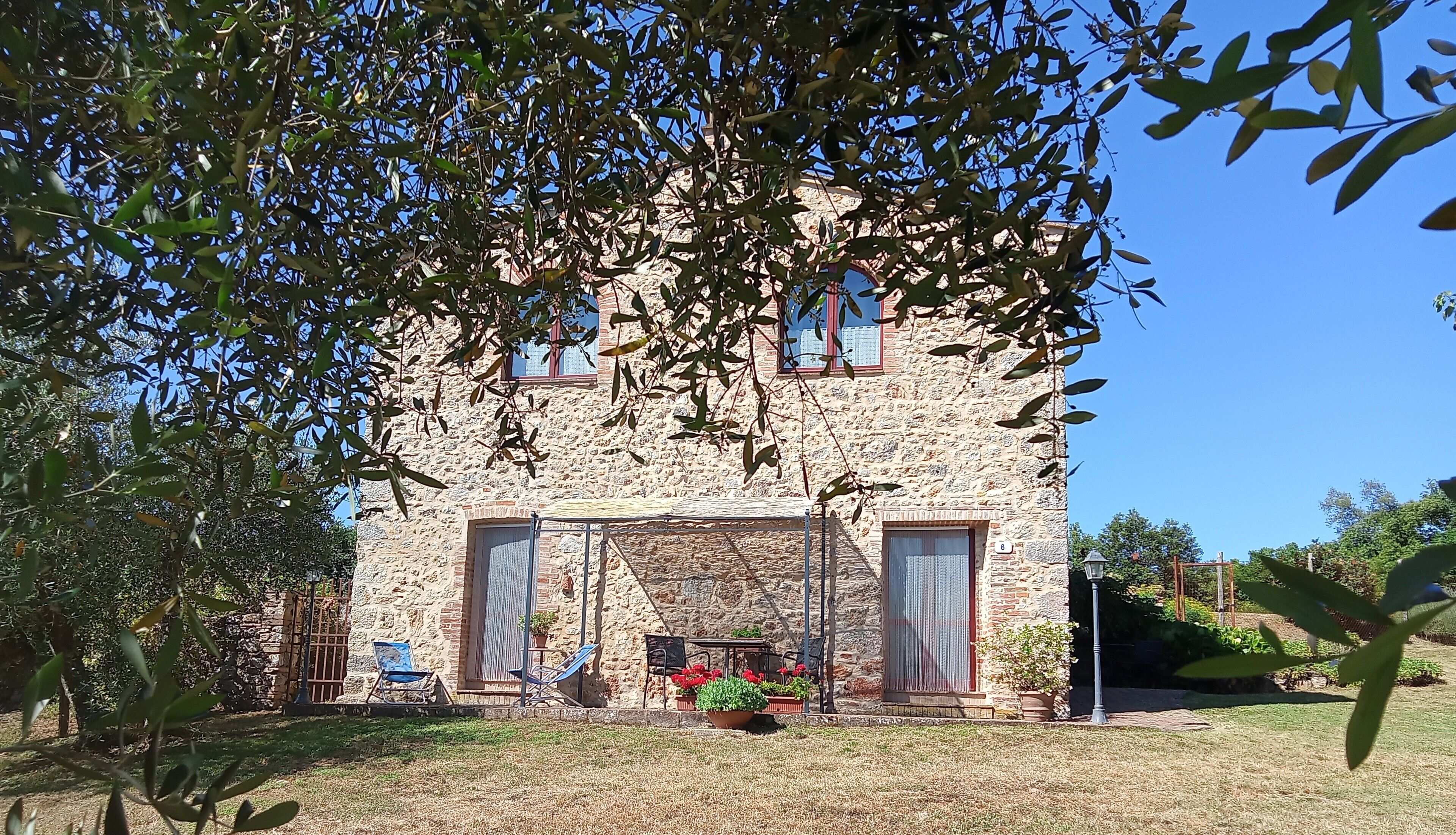 Un edificio de piedra con un amplio ventanal, una puerta y un letrero con el número 6.