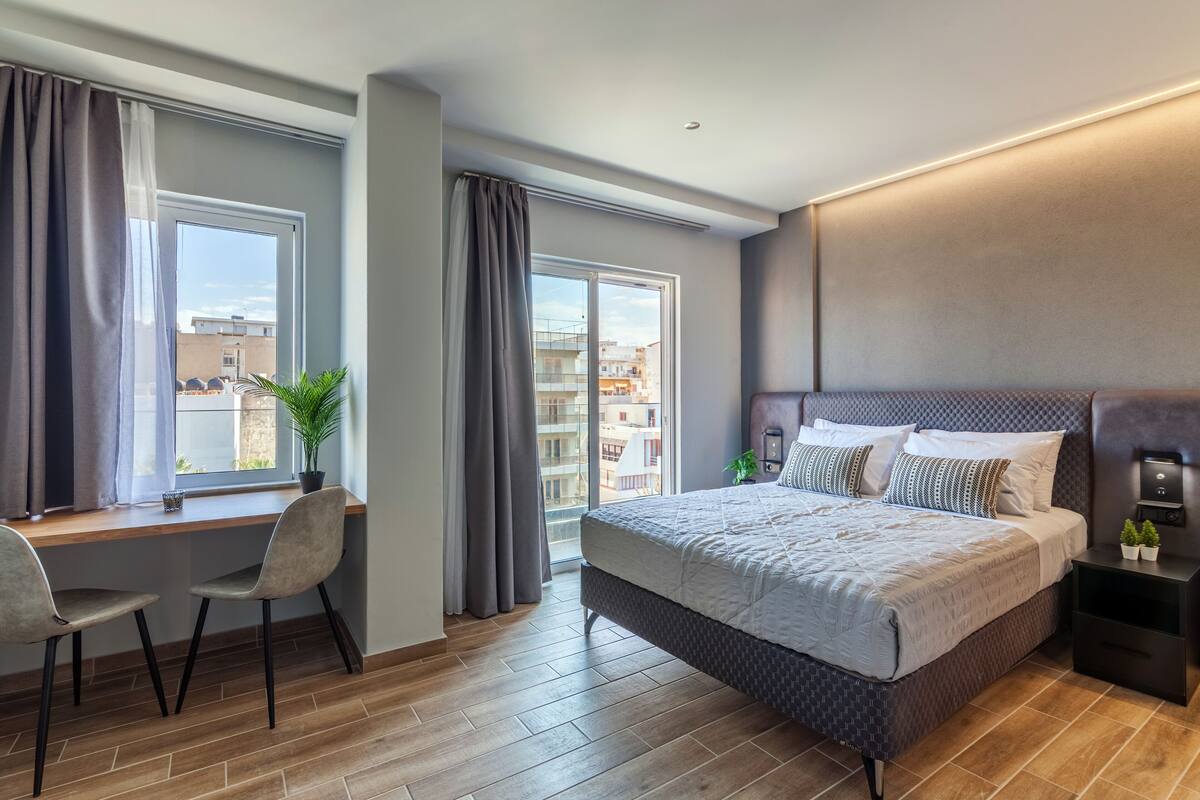 Une chambre moderne avec un grand lit, un bureau et une fenêtre avec des rideaux.