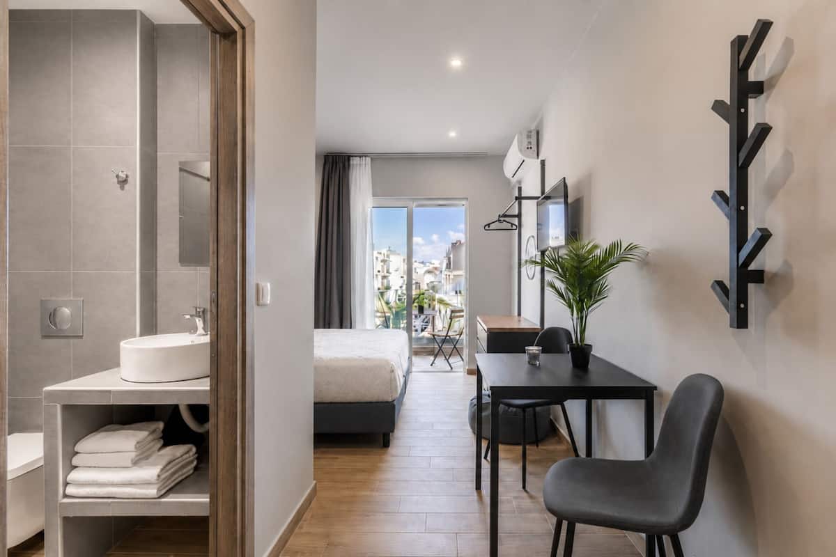 Ett modernt hotellrum med badrum, sÀng, skrivbord och stol.