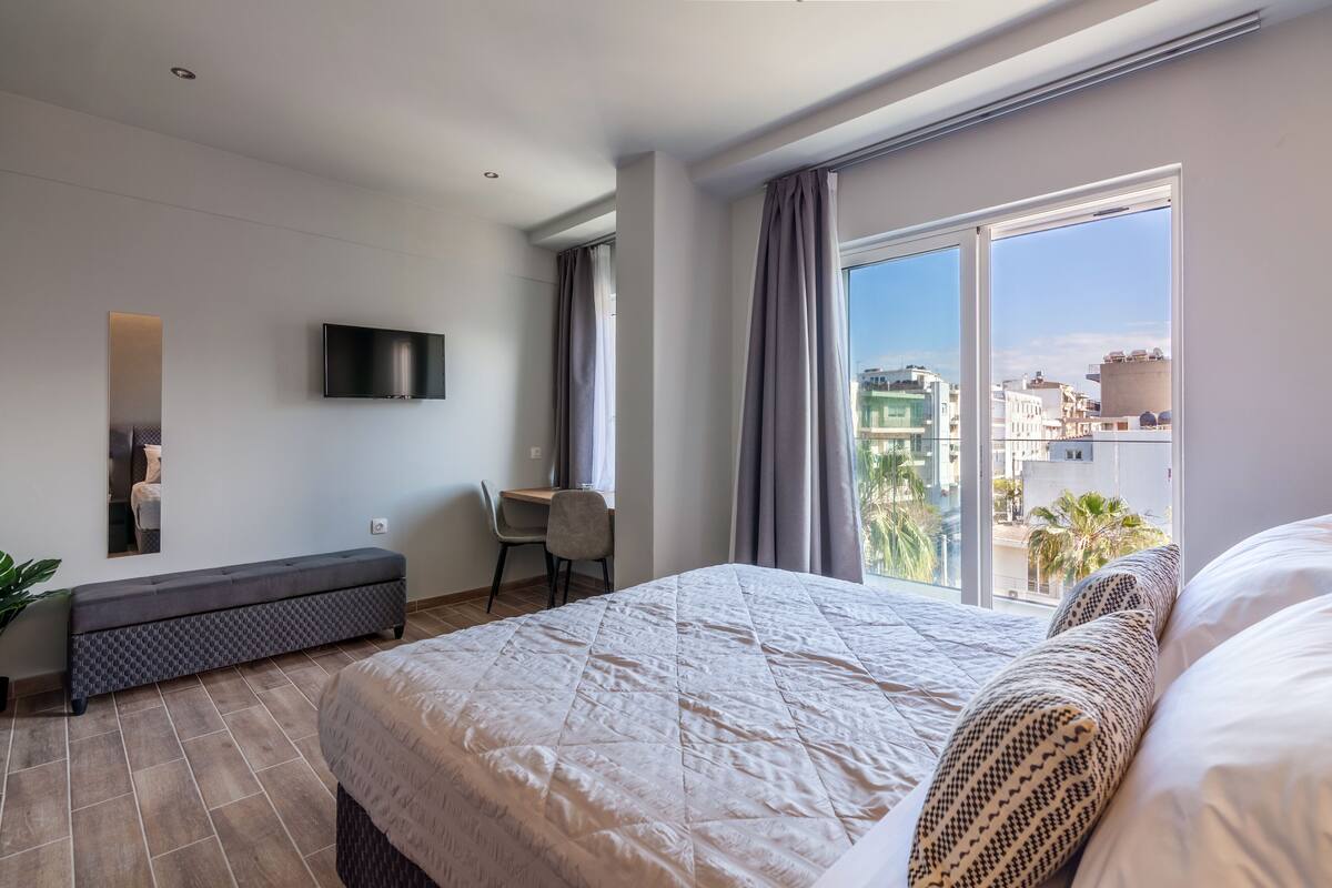 Une chambre d’hôtel moderne, dotée d’un grand lit, d’un bureau et d’un téléviseur fixé au mur.