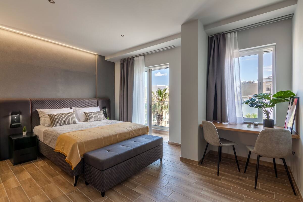 Une chambre moderne avec un grand lit, un bureau et une vue sur l’extérieur.