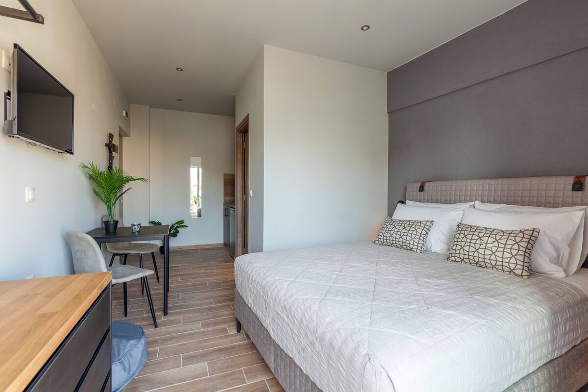 Une chambre moderne avec un grand lit, un bureau avec une chaise et un téléviseur fixé au mur.