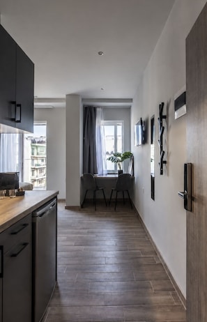 Une cuisine moderne avec des meubles de couleur sombre, un plan de travail en bois et un coin repas comprenant une chaise et une table.