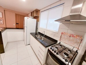 A kitchen with white cabinets, a stainless steel refrigerator, a gas stove, and a window above the sink. - Beach Class Residence Eco Life (Ipojuca)