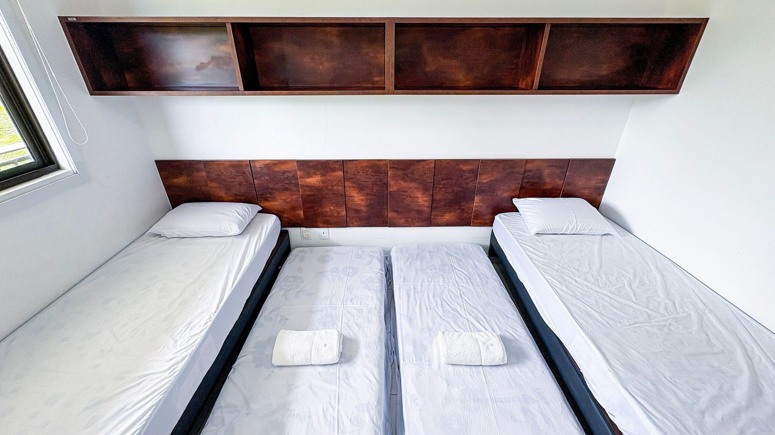 Quarto com cama de casal, cabeceira de madeira, duas almofadas e uma mesinha de cabeceira.