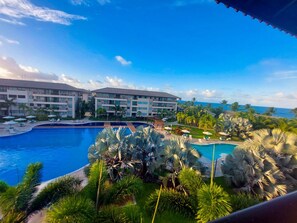 A resort with a large swimming pool, multiple hotel buildings, and palm trees. - Beach Class Residence Eco Life (Ipojuca)